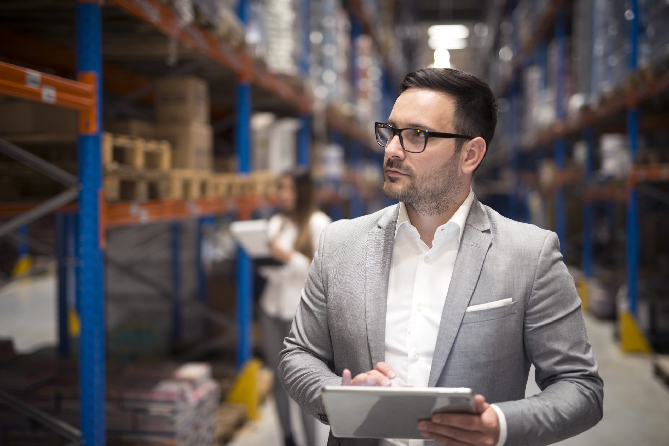 Manager in a warehouse holding a tablet.